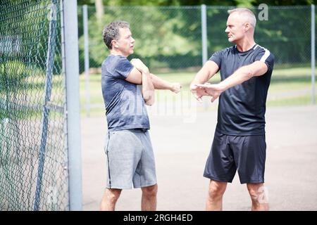 Hommes matures s'étirant par clôture Banque D'Images
