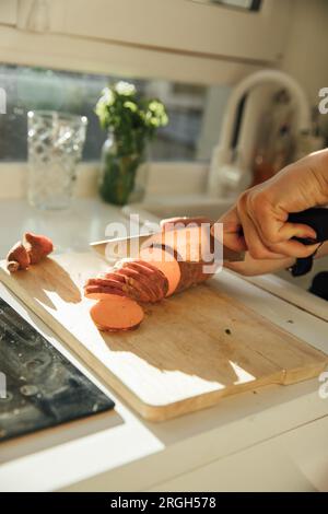 Main de femme tranchant la patate douce Banque D'Images