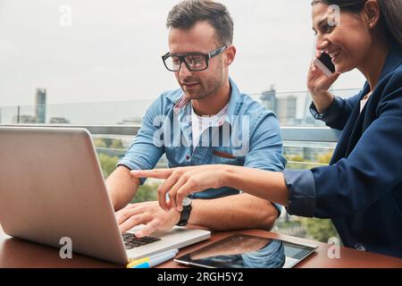 Ordinateur portable à l'aide de collègues et smart phone sur balcon Banque D'Images