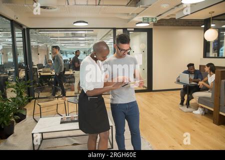 Collègues using digital tablet in office Banque D'Images