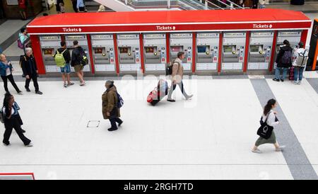 Rangée automatisée de distributeurs de billets à l'intérieur de Liverpool Street Station personnes voyageurs touristes marchant le long du hall avec des sacs à bagages Londres Royaume-Uni Banque D'Images