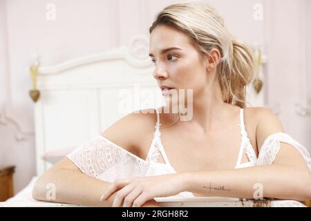 Femme en robe blanche assise près d'une table Banque D'Images