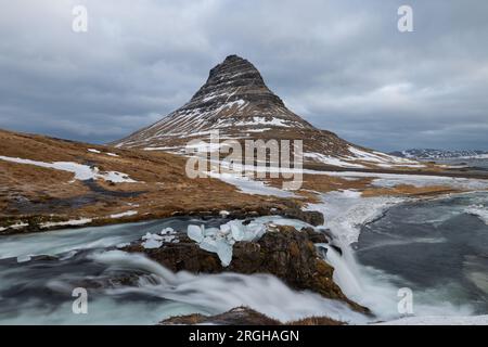 Au pied de la cascade appelée Kirkjufellsfoss qui est à moitié glacé et n'a pas autant d'eau qui coule à travers elle qu'en été. Banque D'Images