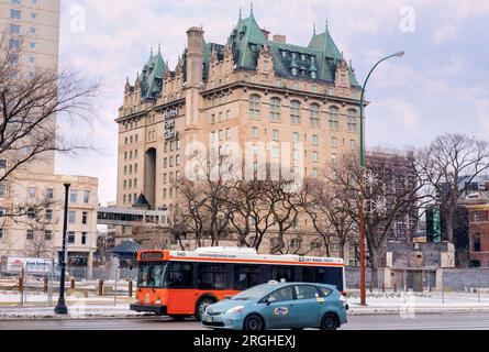 Winnipeg, Manitoba, Canada - 11 17 2014 : autobus orange de Winnipeg Transit et taxi bleu Unicity se déplaçant le long de la rue main en face de l'hôtel fort Banque D'Images