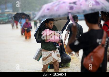 Chattogram, Bangladesh. 09 août 2023. (Un homme tenant un bébé traverse une route inondée à Chattogram, Bangladesh, le 9 août 2023. Des soldats bangladais ont été déployés mardi dans la région de Chattogram, à quelque 240 km au sud-est de la capitale Dhaka, pour faire face à la détérioration de la situation de pluies torrentielles. Trois incidents de glissements de terrain ont coûté la vie à au moins six personnes dans le district de Cox's Bazar à Chattogram lundi, qui abrite aujourd'hui près de 1 millions de réfugiés Rohingyas qui vivent sur les pentes des collines. Crédit : Xinhua/Alamy Live News Banque D'Images