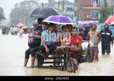 Chattogram, Bangladesh. 09 août 2023. (Un homme pousse un tricycle en transférant des gens à travers une route inondée à Chattogram, Bangladesh, le 9 août 2023. Des soldats bangladais ont été déployés mardi dans la région de Chattogram, à quelque 240 km au sud-est de la capitale Dhaka, pour faire face à la détérioration de la situation de pluies torrentielles. Trois incidents de glissements de terrain ont coûté la vie à au moins six personnes dans le district de Cox's Bazar à Chattogram lundi, qui abrite aujourd'hui près de 1 millions de réfugiés Rohingyas qui vivent sur les pentes des collines. Crédit : Xinhua/Alamy Live News Banque D'Images