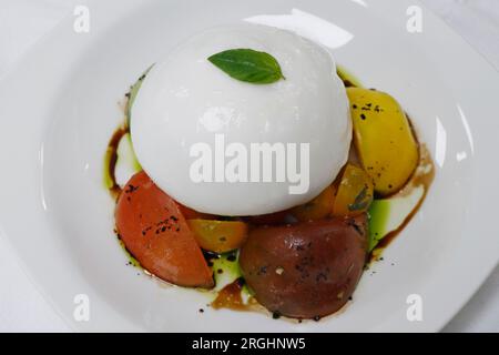 mozzarella de buffle italienne ou burrata avec salade de tomates sur une assiette blanche Banque D'Images
