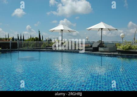 Chaises longues avec parasols au bord de la piscine de l''Amen Restaurant Puncak Bogor Banque D'Images