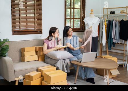 Startup propriétaire de petite entreprise travaillant avec l'ordinateur sur le lieu de travail. Freelance deux femmes vendeur vérifier la commande de produit. Emballage de marchandises pour livraison à Banque D'Images