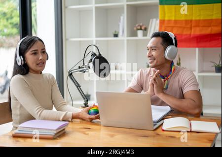 Un podcasteur gay asiatique heureux et gentil ou animateur de radio interviewe son invité spécial dans son studio de diffusion. Banque D'Images