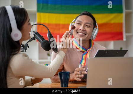 Un podcasteur ou animateur de radio gay asiatique attrayant et joyeux est composé par une invitée féminine dans son émission de radio. Banque D'Images