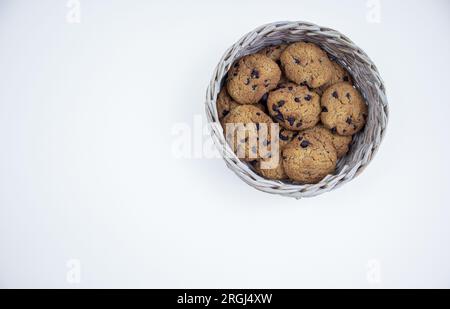 Biscuits aux pépites de chocolat dans un panier en bambou isolé sur fond blanc Banque D'Images