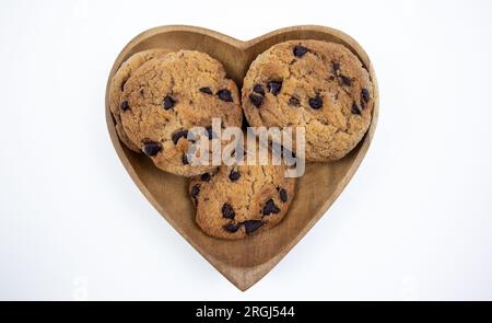 Biscuits aux pépites de chocolat sur une assiette en forme de coeur sur un fond blanc Banque D'Images