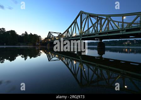 Potsdam, Allemagne. 10 août 2023. Le pont Glienicke se reflète dans l'eau de la rivière Havel le matin. Le pont à la frontière de la ville entre Potsdam et Berlin est un symbole pour surmonter la division entre l'est et l'Ouest. Cette année encore, de nombreux événements du 13 août commémorent la construction du mur et la division de l'Allemagne. Crédit : Soeren Stache/dpa/Alamy Live News Banque D'Images