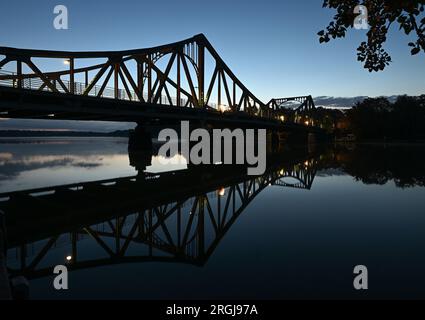 Potsdam, Allemagne. 10 août 2023. Le pont Glienicke se reflète dans l'eau de la rivière Havel le matin. Le pont à la frontière de la ville entre Potsdam et Berlin est un symbole pour surmonter la division entre l'est et l'Ouest. Cette année encore, de nombreux événements du 13 août commémorent la construction du mur et la division de l'Allemagne. Crédit : Soeren Stache/dpa/Alamy Live News Banque D'Images