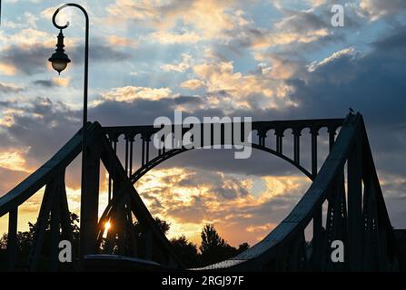 Potsdam, Allemagne. 10 août 2023. Le soleil se lève derrière le pont Glienicker, qui traverse la rivière Havel. Le pont à la frontière de la ville entre Potsdam et Berlin est un symbole pour surmonter la division entre l'est et l'Ouest. Cette année encore, de nombreux événements du 13 août commémorent la construction du mur et la division de l'Allemagne. Crédit : Soeren Stache/dpa/Alamy Live News Banque D'Images