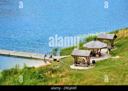 Błaskowizna, Pologne, 24 juillet 2023 : jetée de baignade sur un lac en Mazurie avec abris et baigneurs, vue aérienne Banque D'Images