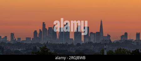 Wimbledon, Londres, Royaume-Uni. 10 août 2023. Un ciel orange à l'aube avec les gratte-ciel lointains du centre de Londres captant les premiers rayons de soleil avec des maisons de banlieue au premier plan. Crédit : Malcolm Park/Alamy Live News Banque D'Images