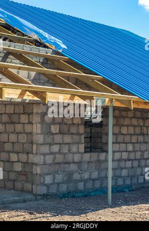 tôles ondulées sur un toit à moitié fait, travaux en cours, mur non fini Banque D'Images