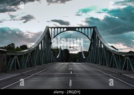 Potsdam, Allemagne. 10 août 2023. Le soleil se lève derrière le pont Glienicker, qui traverse la rivière Havel. Le pont à la frontière de la ville entre Potsdam et Berlin est un symbole pour surmonter la division entre l'est et l'Ouest. Cette année encore, de nombreux événements du 13 août commémorent la construction du mur et la division de l'Allemagne. Crédit : Soeren Stache/dpa/Alamy Live News Banque D'Images