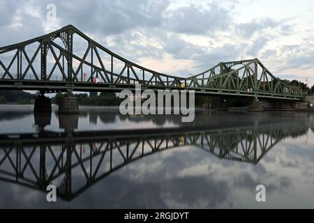 Potsdam, Allemagne. 10 août 2023. Pont Glienicke traversant la rivière Havel reflété dans l'eau de la rivière longue exposition). Le pont à la frontière de la ville entre Potsdam et Berlin est un symbole pour surmonter la division entre l'est et l'Ouest. Cette année, le 13 août, de nombreux événements commémorent la construction du mur et la division de l'Allemagne. Crédit : Soeren Stache/dpa/Alamy Live News Banque D'Images