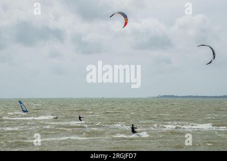 Kitesurfers et windsurfers sur le Solent dans le Hampshire en Angleterre avec l'île de Wight en arrière-plan Banque D'Images