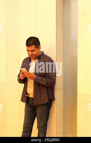 Homme latino-américain de 40 ans aux cheveux foncés utilise son téléphone portable pour travailler, passer des appels et envoyer des messages, avoir des dates et magasiner en ligne très heureux et satisfait Banque D'Images