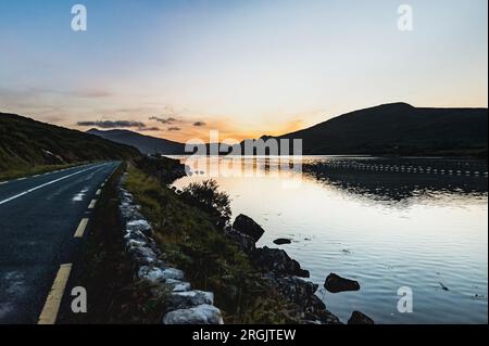 Killary Harbour ou Fjord au coucher du soleil avec la route panoramique Connemara boucle et l'immense océan dans le fjard. Soleil couchant sur la côte ouest irlandaise Banque D'Images