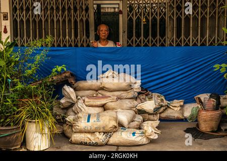 Un résident âgé de Bangkok se prépare à l'inondation avec des sacs de sable devant son magasin, Sukhumvit Road, Bangkok, Thaïlande. Crédit : Kraig Lieb Banque D'Images