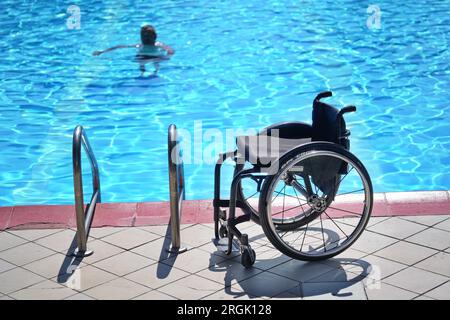 Fauteuil roulant vide dans la piscine pour la réhabilitation des personnes handicapées dans l'eau. Banque D'Images