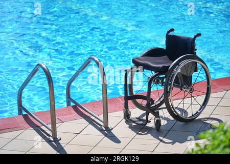 Fauteuil roulant vide dans la piscine pour la réhabilitation des personnes handicapées dans l'eau. Banque D'Images