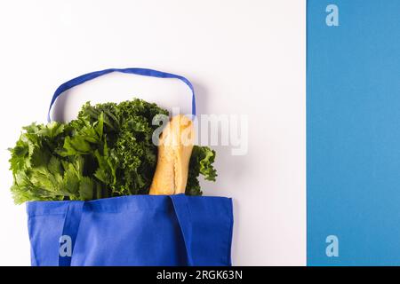 Sac en toile bleu avec baguette et légumes à salade verts et espace de copie sur fond blanc et bleu Banque D'Images