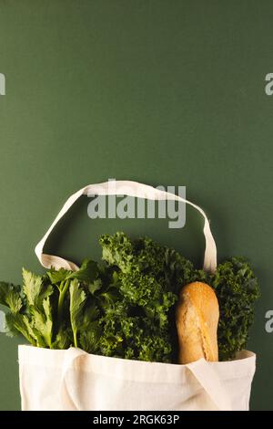 Sac en toile blanche avec baguette et légumes de salade verts et espace de copie sur fond vert Banque D'Images