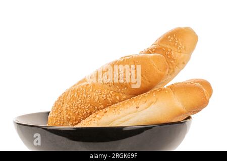 Quatre bagels parfumés saupoudrés de graines de sésame dans une assiette en céramique noire, gros plan, isolés sur blanc. Banque D'Images