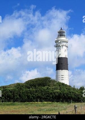 Phare blanc avec une bande noire derrière une prairie et maisons devant un ciel nuageux sur l'île sylt Banque D'Images