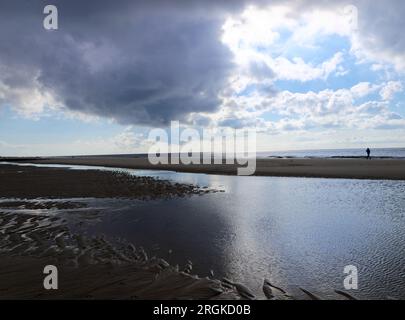 Plage principale de Westerland sur l'île de Sylt. Panorama au coucher du soleil avec ciel nuageux coloré, horizon et reflets à marée basse. Banque D'Images