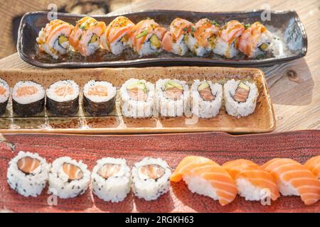 D'en haut de sushi appétissant ensemble composé de Philadelphie et California rouleaux tekkamaki et nigiri saké servis sur des plateaux en céramique placés en rangée Banque D'Images