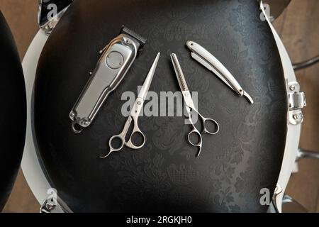 Vue de dessus de diverses fournitures de coiffure placées sur une chaise noire dans un salon de coiffure professionnel Banque D'Images