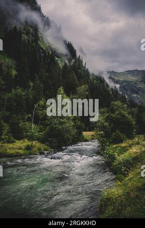 Une petite rivière dans la vallée entre les montagnes, en arrière-plan une belle cascade Banque D'Images