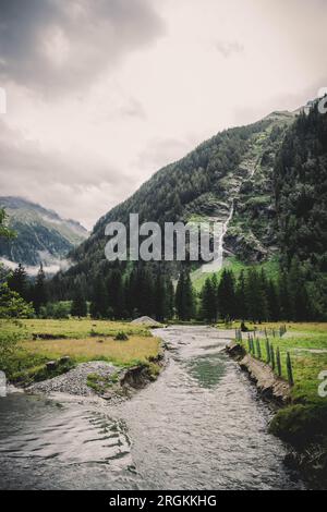 Une petite rivière dans la vallée entre les montagnes, en arrière-plan une belle cascade Banque D'Images