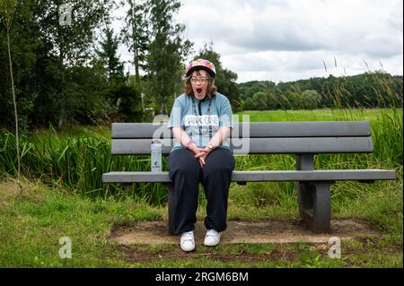 Meerhout, Anvers, Belgique - 1 août 2023 - Femme baillée de 40 ans avec le syndrome de Down, assise sur un banc en plein air Banque D'Images