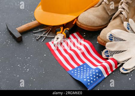 Composition avec équipement de protection, outils et drapeau américain sur fond grunge gris. Célébration de la fête du travail Banque D'Images