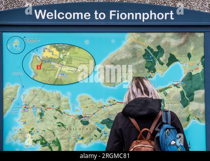 Touriste féminine regardant une grande carte sur un mur à Fionnphort sur l'île de Mull, en Écosse, où les ferries font le court voyage à l'île d'Iona Banque D'Images