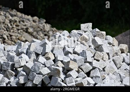 Matériau de construction préparé pour la construction et la reconstruction de la grande chaussée pour les piétons à travers le village tchèque Vidče. Briques cubes de granit. Banque D'Images