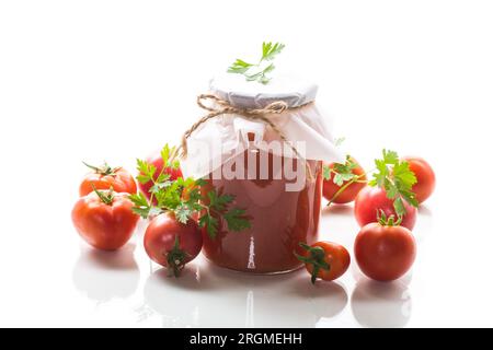 Jus de tomate maison cuit en conserve dans un pot de tomates naturelles, isolé sur fond blanc. Banque D'Images