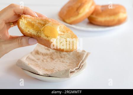 Bolas de Berlim, Berliner ou beignets farcis à la confiture d’œufs, un dessert très populaire dans les pâtisseries portugaises. Personne goûtant un bal de berlin. Banque D'Images