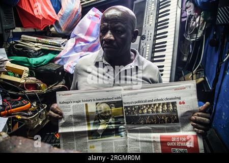 Josephat Mureithi, 54 ans, frère du journaliste kenyan tué William Munuhe, expose un vieux journal kenyan qui a couvert l'histoire du fugitif présumé du génocide rwandais Felicien Kabuga dans son atelier de réparation d'appareils électroniques dans la ville de Nakuru. La famille du regretté journaliste kenyan William Munuhe, tué le 14 janvier 2003, alors qu'il aidait la police et le FBI à retrouver Felicien Kabuga. Felicien Kabuga, 87 ans, le cerveau présumé du génocide rwandais malade, devrait être libéré à la suite du mécanisme international résiduel des Nations Unies pour le CRIM Banque D'Images