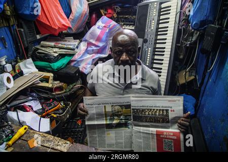 Josephat Mureithi, 54 ans, frère du journaliste kenyan tué William Munuhe, expose un vieux journal kenyan qui a couvert l'histoire du fugitif présumé du génocide rwandais Felicien Kabuga dans son atelier de réparation d'appareils électroniques dans la ville de Nakuru. La famille du regretté journaliste kenyan William Munuhe, tué le 14 janvier 2003, alors qu'il aidait la police et le FBI à retrouver Felicien Kabuga. Felicien Kabuga, 87 ans, le cerveau présumé du génocide rwandais malade, devrait être libéré à la suite du mécanisme international résiduel des Nations Unies pour le CRIM Banque D'Images