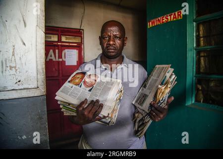 Josephat Mureithi, 54 ans, frère du journaliste kenyan tué William Munuhe, porte de vieux journaux kenyans qui ont couvert l'histoire du fugitif présumé du génocide rwandais Felicien Kabuga dans son atelier de réparation d'appareils électroniques dans la ville de Nakuru. La famille du regretté journaliste kenyan William Munuhe, tué le 14 janvier 2003, alors qu'il aidait la police et le FBI à retrouver Felicien Kabuga. Felicien Kabuga, 87 ans, le cerveau présumé du génocide rwandais malade, devrait être libéré à la suite du mécanisme international des Nations Unies chargé d'exercer les fonctions résiduelles des Nations Unies pour Crimina Banque D'Images