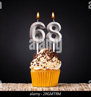 Cupcake d'anniversaire avec bougie numéro 68 - célébration sur fond sombre Banque D'Images